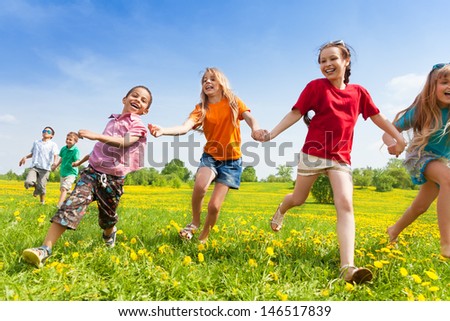 Diversity looking kids, boys and girls running in the yellow flowers spring field