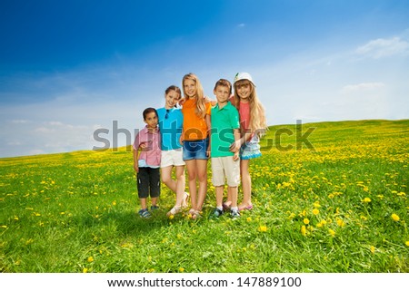 Five happy diversity looking children friends standing in the flower field