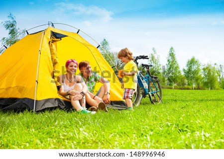 Young couple with kid sitting in the tent on a bike hiking trip