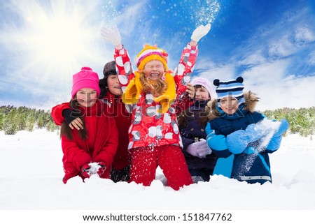 Group of five happy kids, boys and girls throw snow in the air