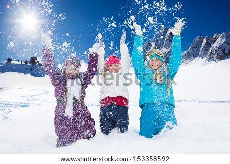 Three happy 10 years old girls throwing snow in the air at once