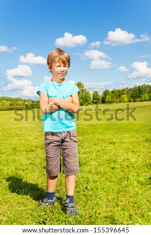 Full height portrait of on nice Caucasian boy with blond standing in the park on sunny summer day
