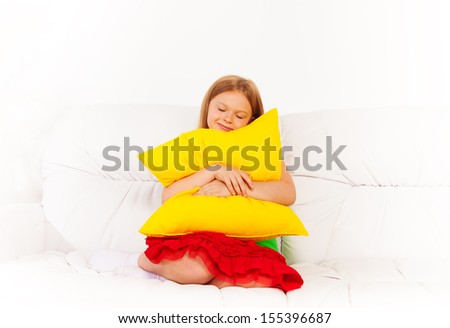 One happy calm sleepy and relaxed girl 6 years old sitting with pillow on the white leather coach