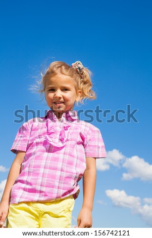 Cute smiling 5 years old girl standing outside with sky on background