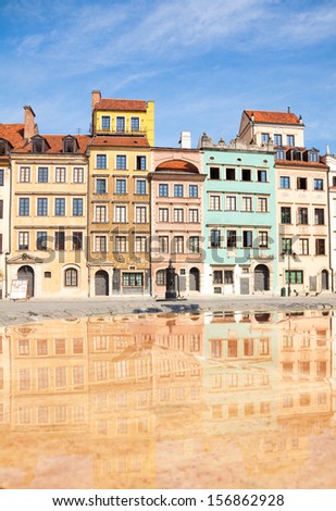 Reflecting surface of fountain and Warsaw old town marketplace square and colorful houses
