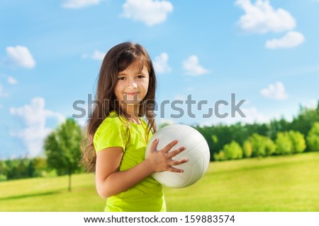Happy girl standing in the park with volley ball smiling and looking at camera