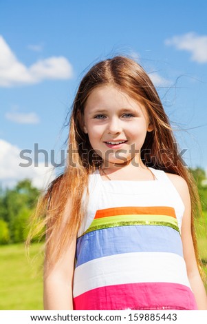 Beautiful portrait of beautiful little little girl with long hairs standing outside on sunny day