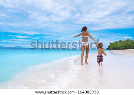 happy family walking on white sand beach