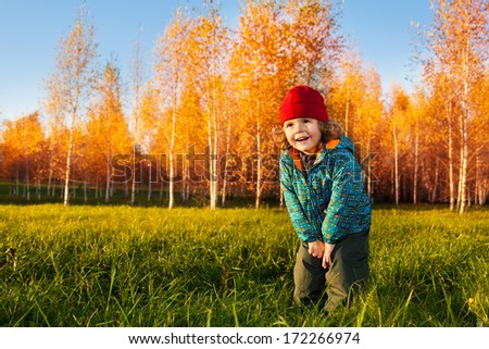 Happy 3 years old boy stand and laugh in the autumn park in October