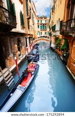 Gondola On Venice Canal With Houses And Bridge On The Street