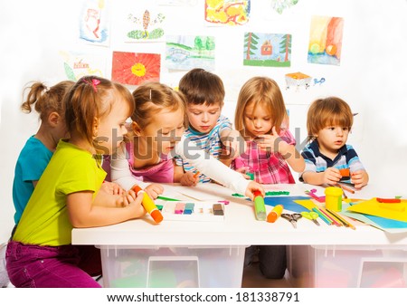 Large group of little kids on painting class sitting together with pencils and paints
