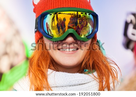 Happy young woman in ski mask with reflection of her friends on the mask