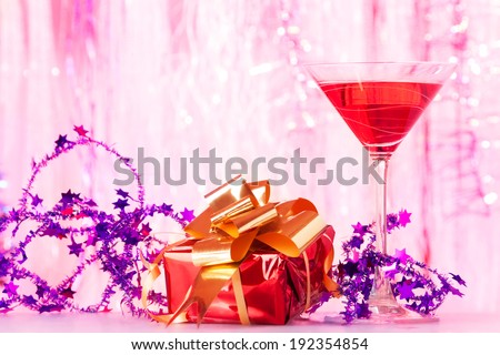 Cocktail glass with alcohol cocktail Christmas decoration and red small present with gold ribbon