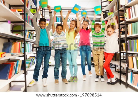 Six children with hands up hold exercise books