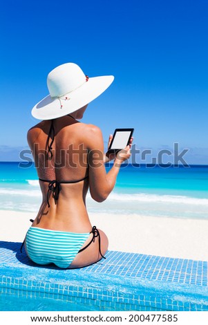 Beautiful woman from back reads ebook with hat