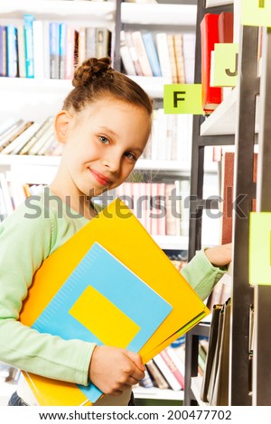 Schoolgirl searches books and holds exercise book