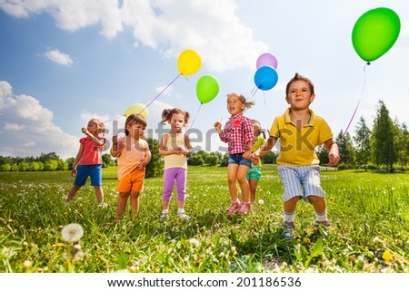 Children with colorful balloons running in field