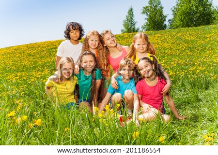 Eight kids sitting together on the green grass