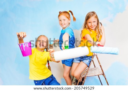 Three girls smile against the background of wall