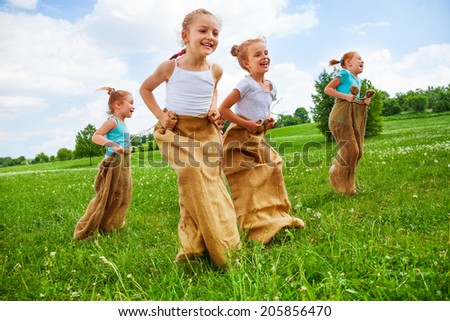 Children having fun jumping in sacks on a meadow