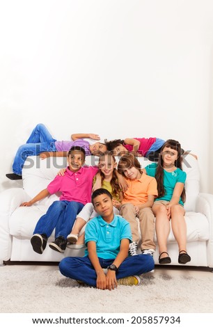 Group of nice smiling boys and girls sitting and laying on the coach at living room