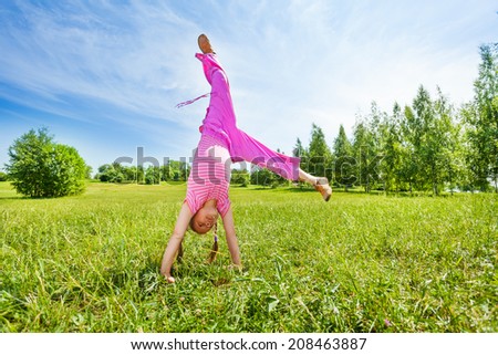 Girl making flip on grass standing upside down