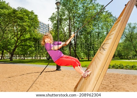 Girl climbing on wooden construction in the park