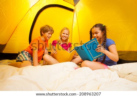 Three kids reading books in a tent