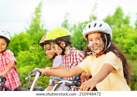 Small cute girl in helmet holds bike handle-bar