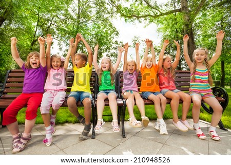 Funny group of kids on bench with arms up