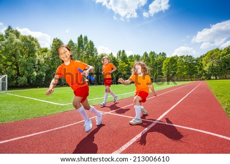 Three girls with one relay baton running