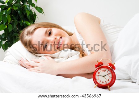 Positive woman smile laying in bed with red alarm