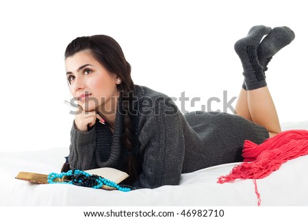 Calm woman in wool tunic writing her dairy laying in bed