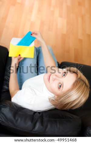 Woman sitting on a couch and opening envelope