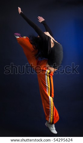 Woman in dance move with her hands up, on dark background