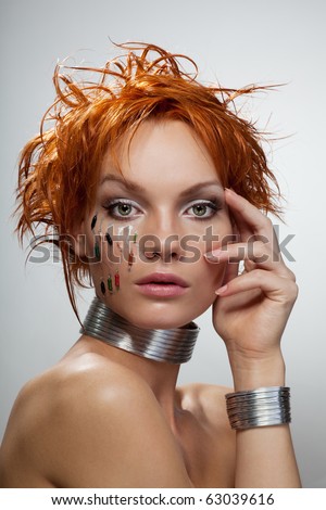 Studio fashion portrait of young futuristic woman with chips on her face and grey background