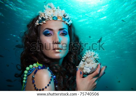Beauty shoot of a woman underwater with coral in her hands and crown made of
