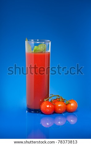 Tomato juice on blue with small cherry tomato vine