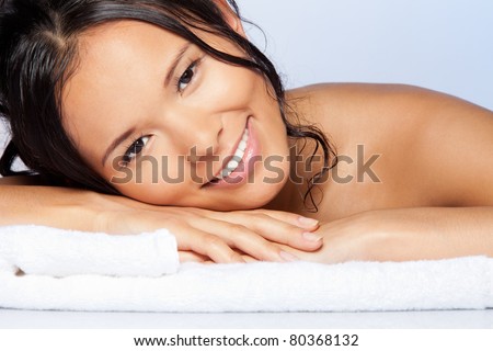 Happy young Asian girl laying on the towel and smiling with wet hairs