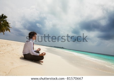 Calm businessman sitting on the shore on the white sand