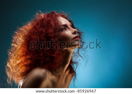 Beauty Portrait of a curly red hair woman on blue