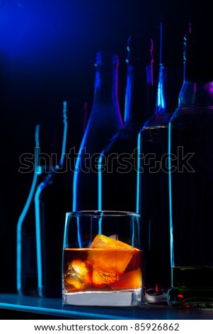 Close-up of whiskey drink and bottles standing on the bar