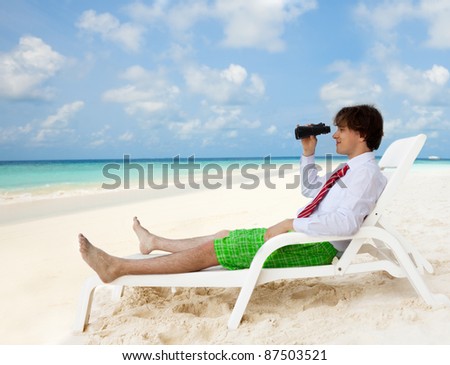 Businessman sitting on the deckchair and looking through binoculars, wearing formal shirt and red tie