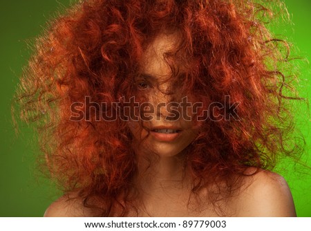 Red curly hair woman beauty portrait with her face partly hidden on the green background
