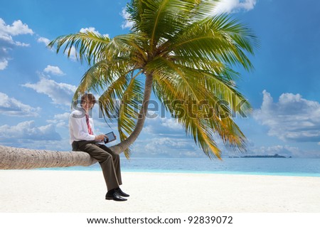 Office manager with tablet pc sitting on palm tree on the Maldivian beach and looking at camera smiling