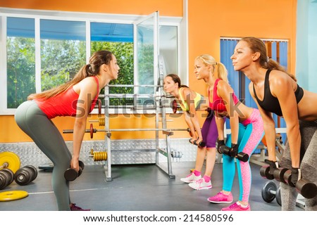 Instructor, young women exercising with dumbbells