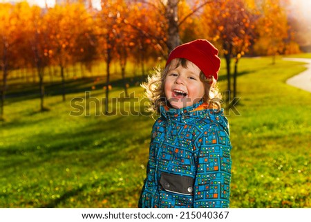 Laughing three years old little boy standing in the autumn park