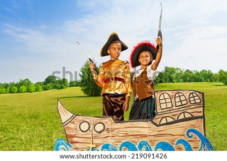 Two black boys in pirates costumes hold  swords up