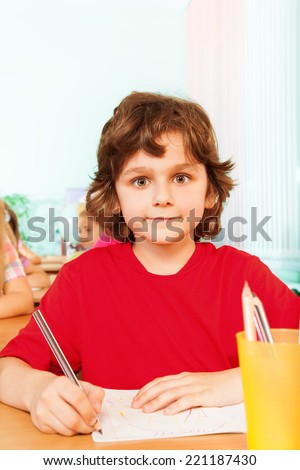 Boy looking straight and writing in exercise book