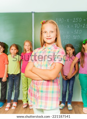 Smiling girl with arms crossed near chalkboard